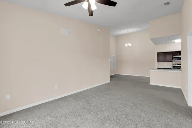 an empty room with a kitchen and a chandelier fan