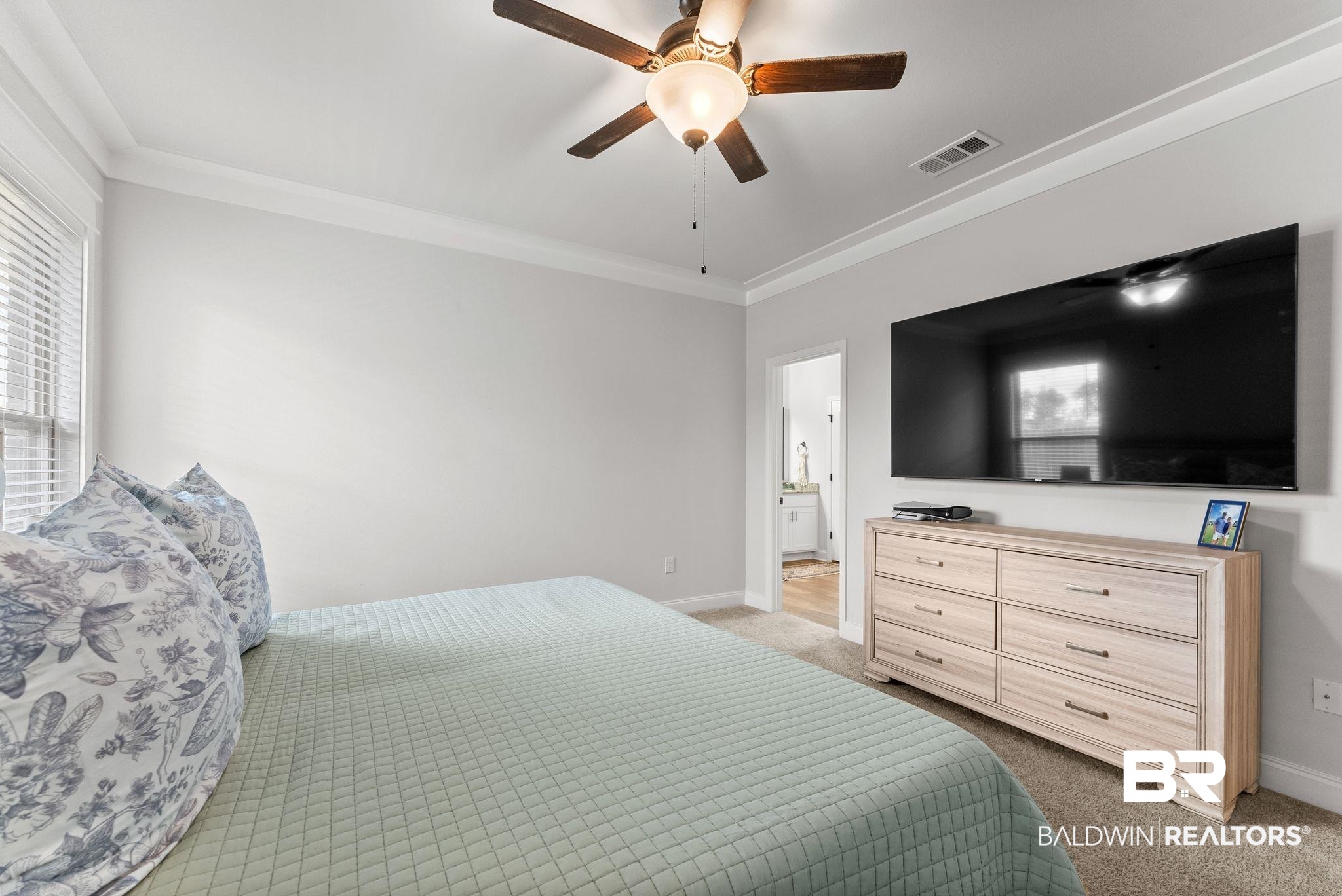 10745 Brodick Loop Daphne, AL 36527 - Photo 19 of 39 Bedroom featuring light colored carpet, ceiling fan, crown molding, and connected bathroom