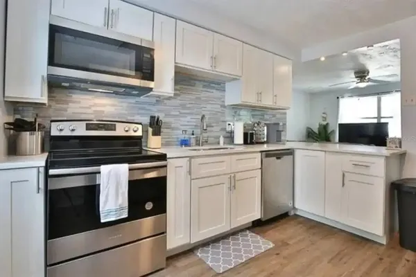 a kitchen with cabinets stainless steel appliances and wooden floor