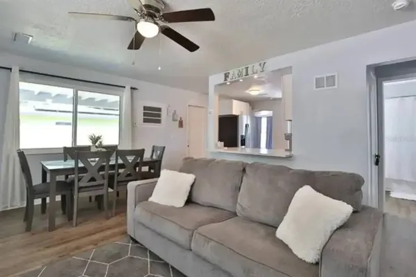 a living room with furniture kitchen view and a large window