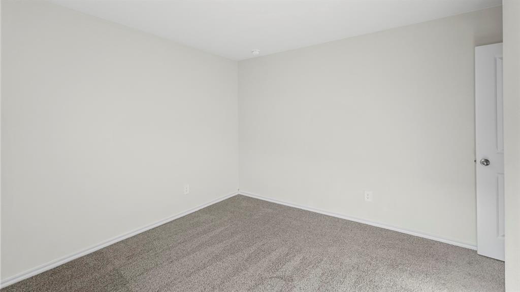 1953 Freeman Street Tyler, TX 75704 - Photo 26 of 32 Interior room featuring light gray wall paint, gray carpet flooring, white baseboards, and a white door with a polished chrome knob
