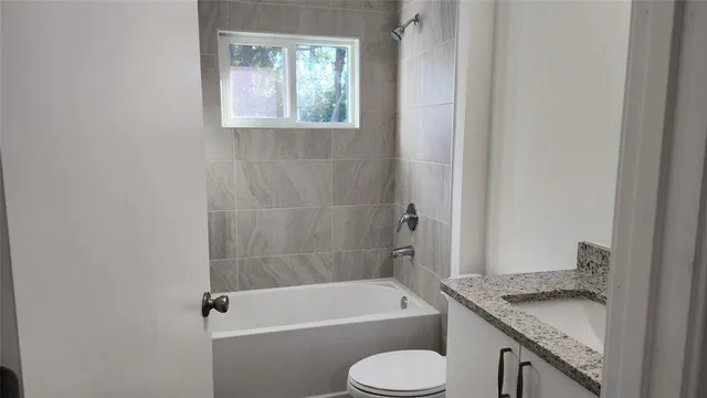 a bathroom with a granite countertop toilet a sink and bathtub