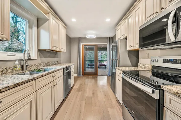 a large kitchen with a stove top oven a sink a microwave and wooden floor