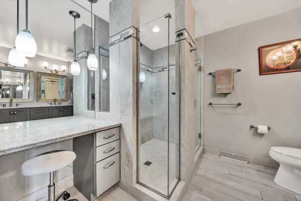 a bathroom with a granite countertop sink a toilet a mirror and shower