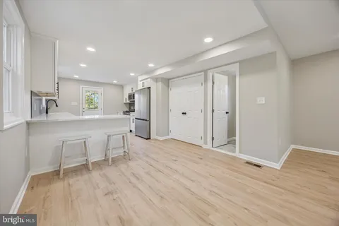 a large white kitchen with a sink dishwasher a stove and white cabinets with wooden floor