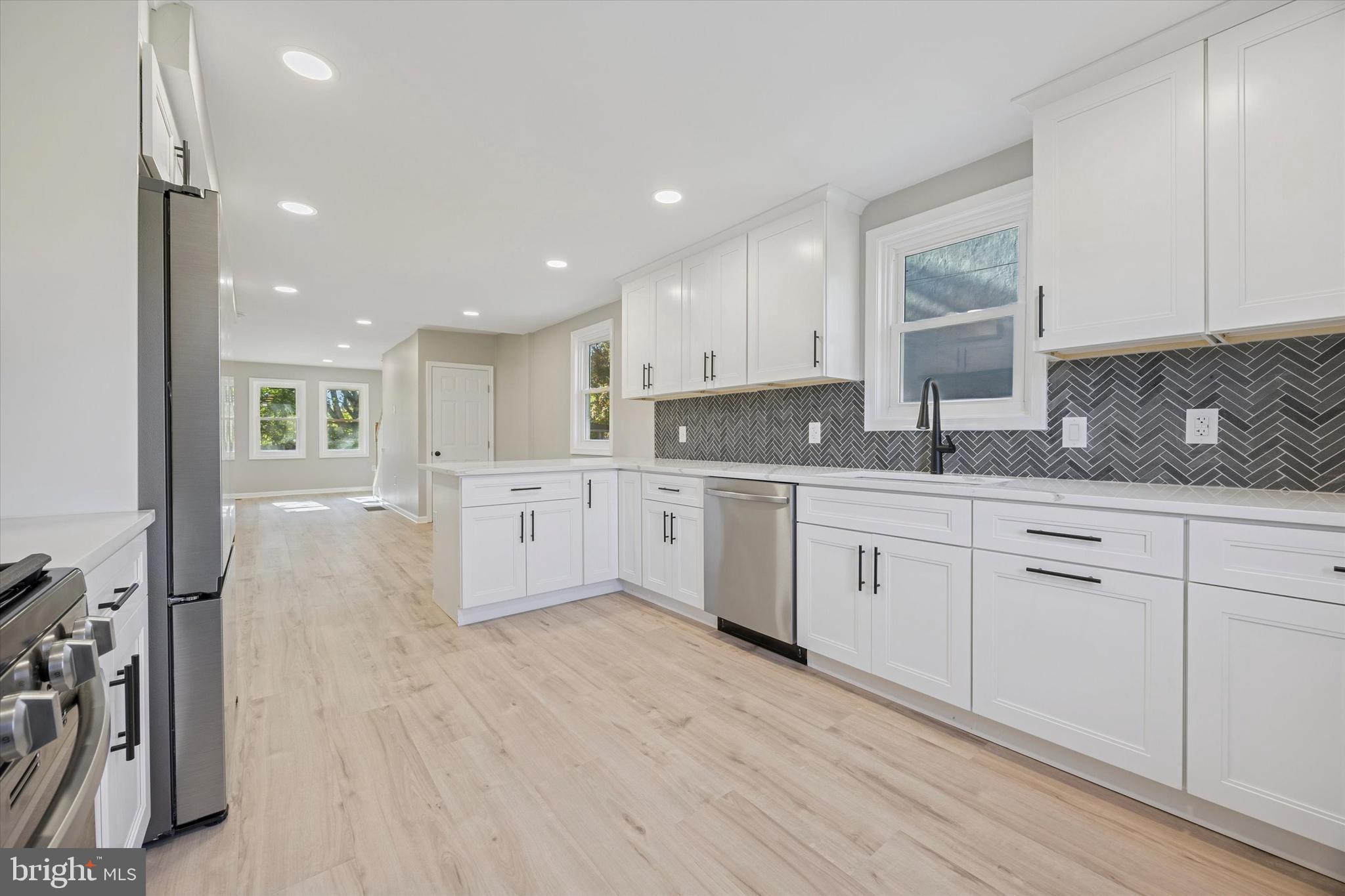 3011 Church Road Lafayette Hill, PA 19444 - Photo 9 of 30 a large white kitchen with a sink dishwasher a stove and white cabinets with wooden floor