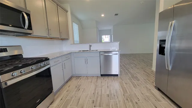 a kitchen with stainless steel appliances granite countertop a stove a sink and a microwave