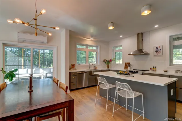 a kitchen with stainless steel appliances granite countertop a stove a refrigerator a sink a dining table and chairs with wooden floor