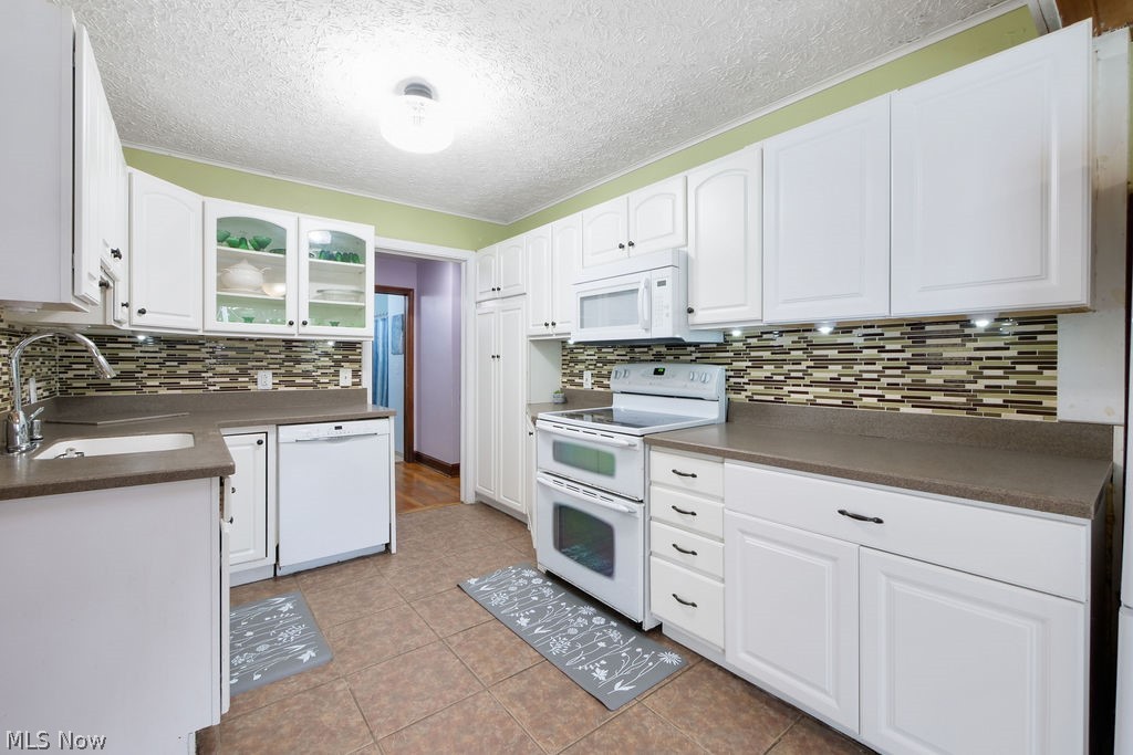 1412 Graham Road Silver Lake, OH 44224 - Photo 25 of 50 Kitchen with white cabinets, white appliances, sink, light tile patterned floors, and backsplash