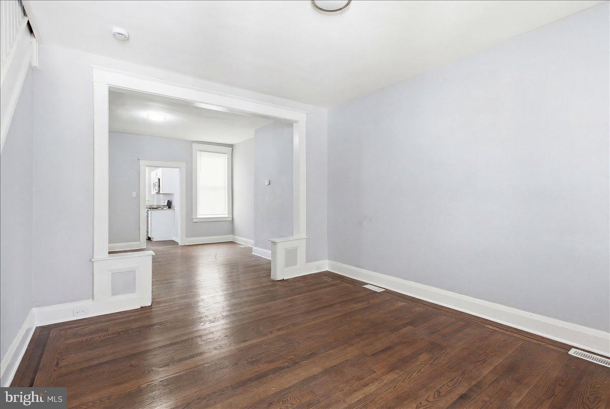 1231 North Potomac Street Baltimore, MD 21213 - Photo 3 of 25 a view of an empty room with wooden floor and a bathroom
