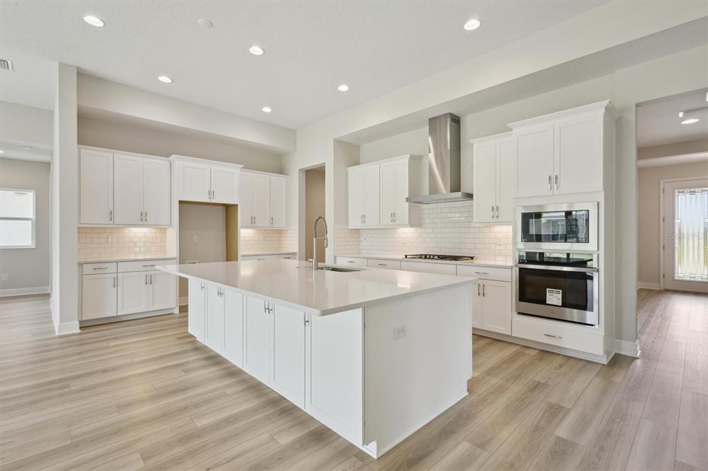 5178 Everlong Drive Apollo Beach, FL 33572 - Photo 12 of 25 a large kitchen with stainless steel appliances granite countertop a large counter top and a stove top oven