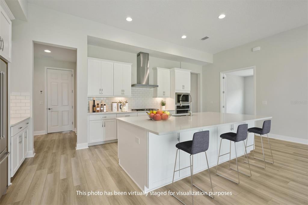 5178 Everlong Drive Apollo Beach, FL 33572 - Photo 2 of 25 a kitchen with kitchen island a stove a refrigerator and a sink with wooden floor