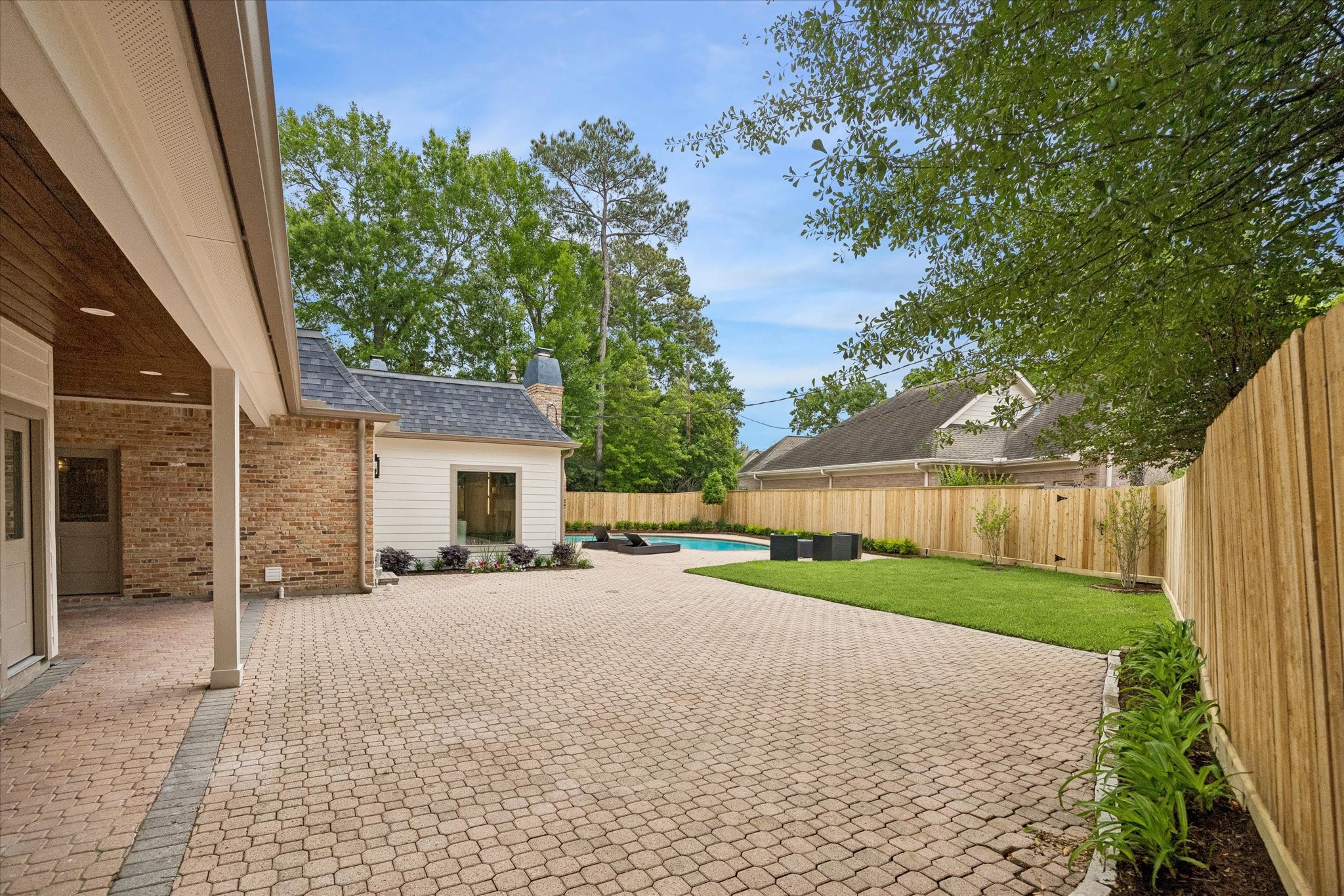 620 Stoneleigh Drive Houston, TX 77079 - Photo 36 of 39 Expansive paved patio offers a private outdoor retreat with generous seating areas, lush green space, and a fully fenced yard, all leading to a sparkling pool—ideal for both relaxing and entertaining.