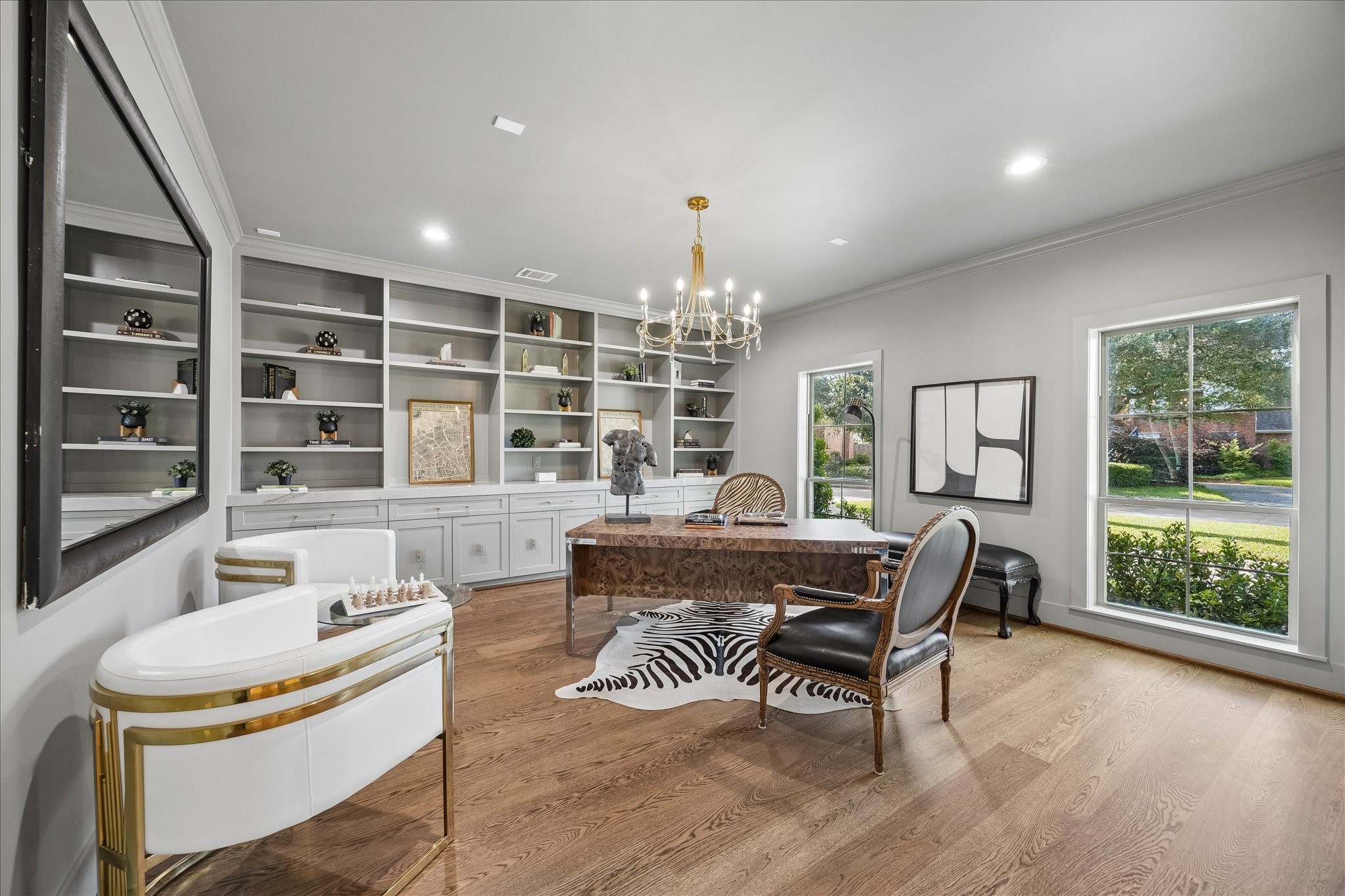 620 Stoneleigh Drive Houston, TX 77079 - Photo 5 of 39 A thoughtfully curated study designed for both sophistication and comfort, featuring rich oak hardwood floors and custom built-in cabinetry that spans the wall with tailored elegance. A statement chandelier casts a soft, refined glow, completing the space.