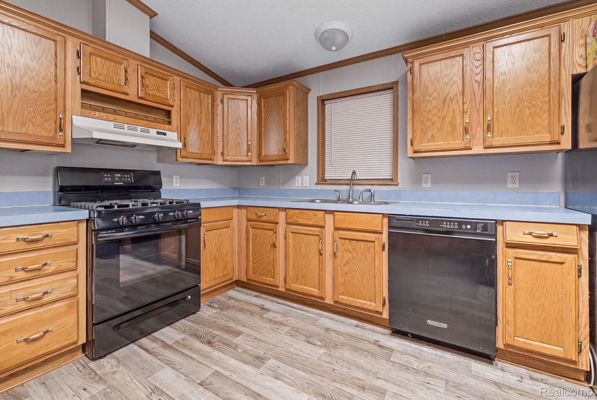 19921 Rhapsody Drive Clinton Township, MI 48036 - Photo 3 of 19 Kitchen featuring wood cabinetry, light blue countertops, black gas range, black dishwasher, and wood-finish flooring