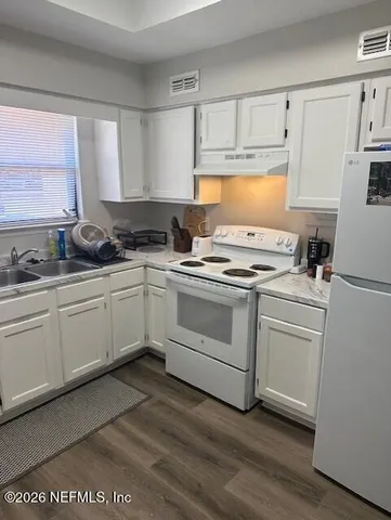 a kitchen with white cabinets appliances a sink and a window