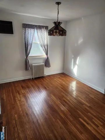 a view of empty room with wooden floor and window