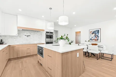 a large white kitchen with lots of counter space sink and cabinets