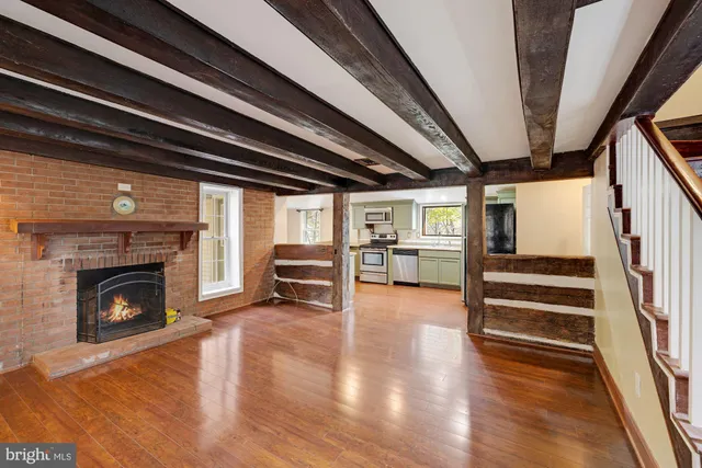 a view of an empty room with wooden floor fireplace and a window