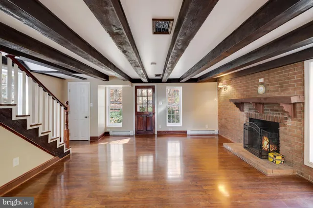 a view of an empty room with wooden floor fireplace and a window