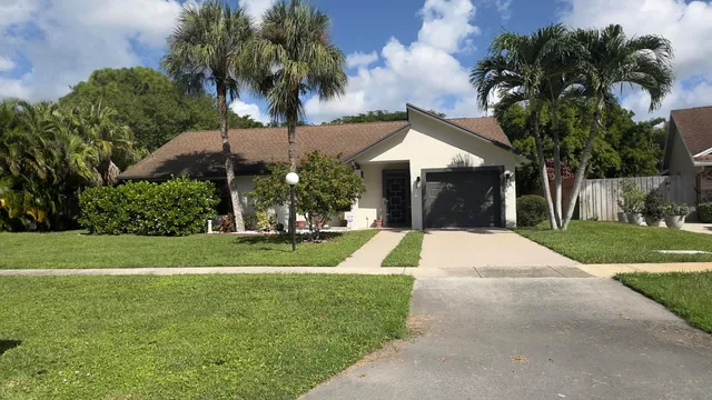 a view of a house with a yard and palm trees