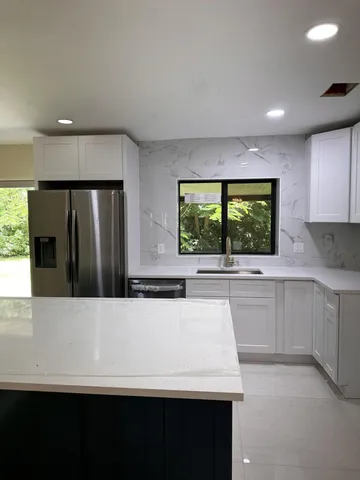 a kitchen with a sink a large window and a refrigerator