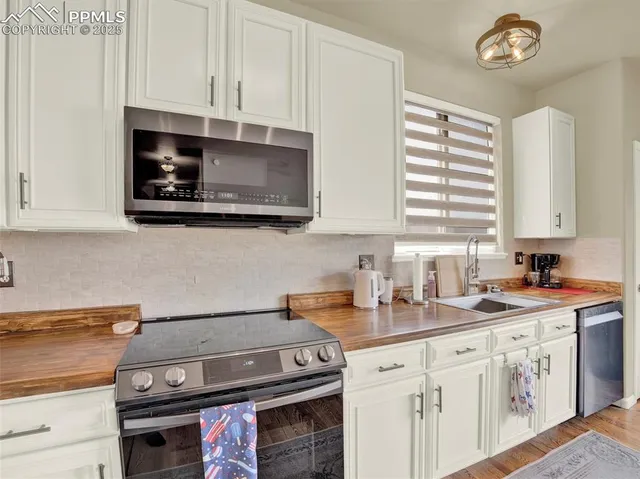 a kitchen with stainless steel appliances kitchen island granite countertop a table chairs stove and microwave