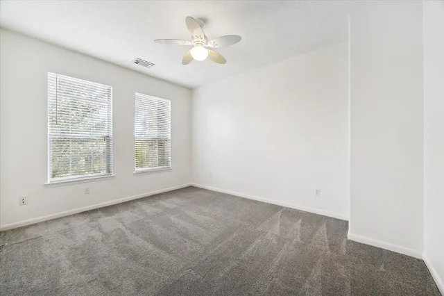 an empty room with a chandelier fan and windows