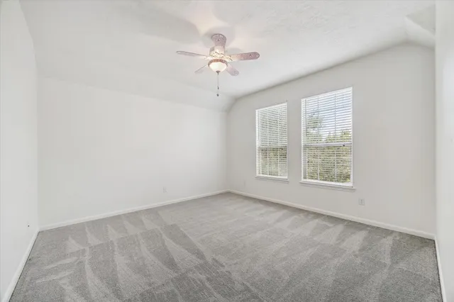 an empty room with ceiling fan and window