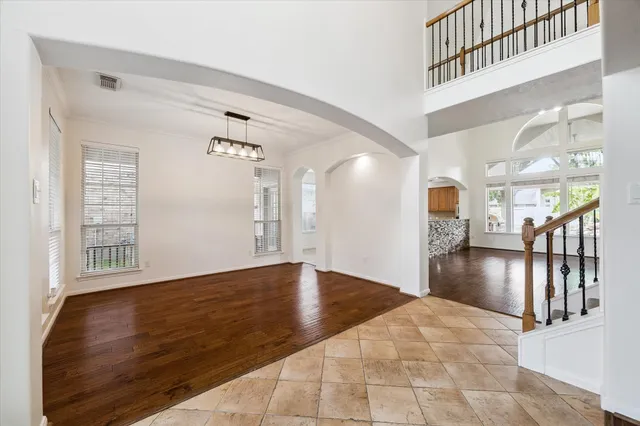 a view of an empty room with wooden floor fridge and a window
