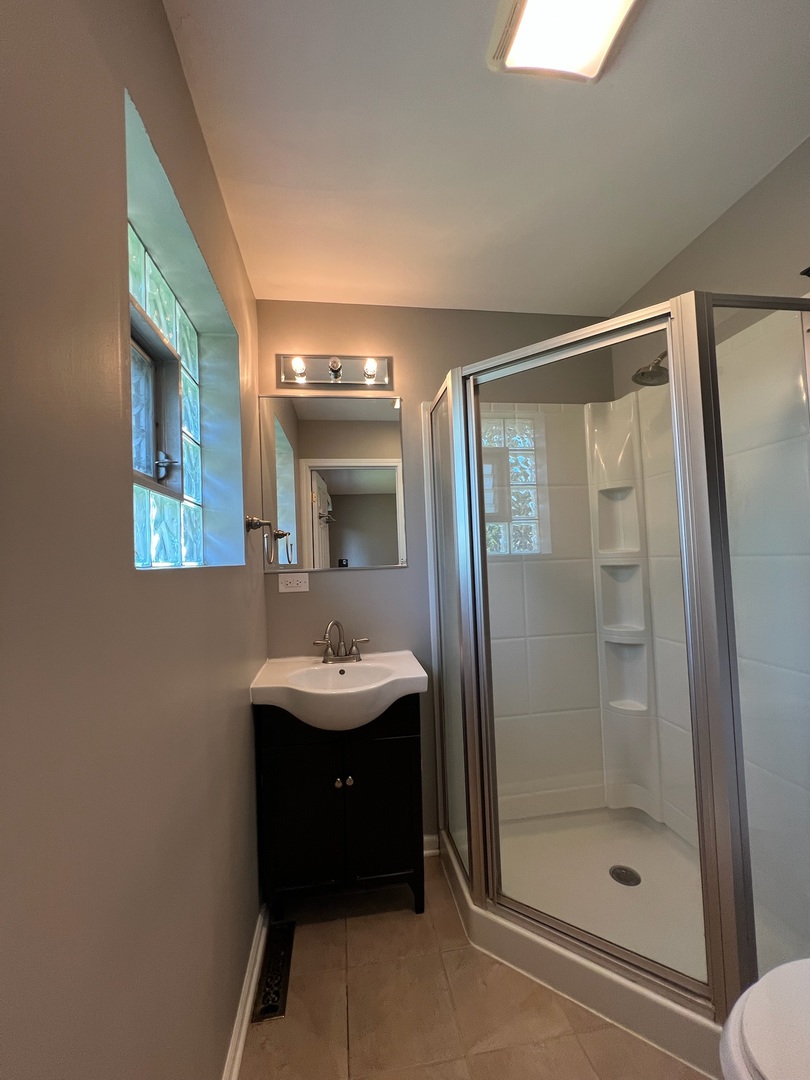 548 Delaware Trail Carol Stream, IL 60188 - Photo 11 of 26 a bathroom with a shower a mirror and a sink