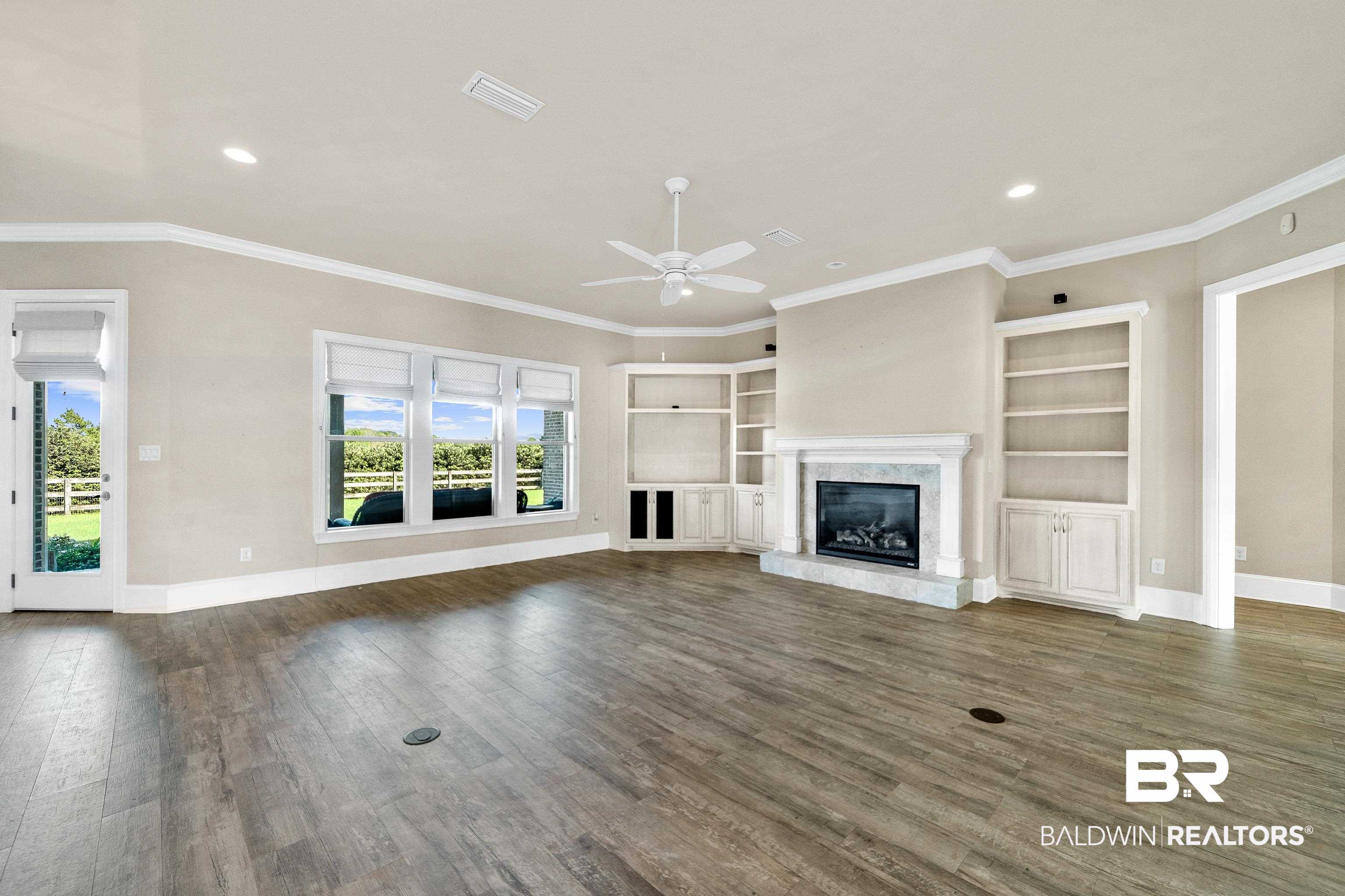 17663 Burwick Loop Fairhope, AL 36532 - Photo 10 of 41 Unfurnished living room featuring a premium fireplace, ceiling fan, dark hardwood / wood-style floors, and crown molding