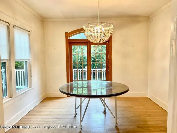 a front view of a dining room with furniture wooden floor and chandelier