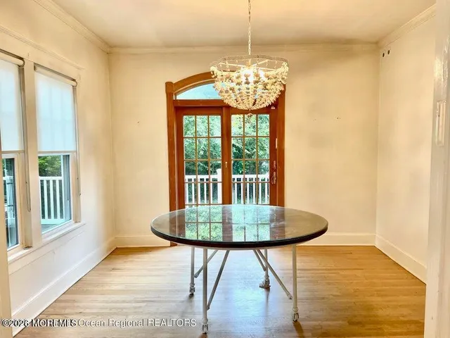 a front view of a dining room with furniture wooden floor and chandelier