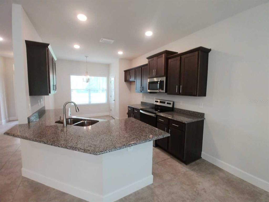 4380 Southwest 92nd Pl Road Ocala, FL 34476 - Photo 4 of 57 a kitchen with kitchen island granite countertop a sink a stove and microwave