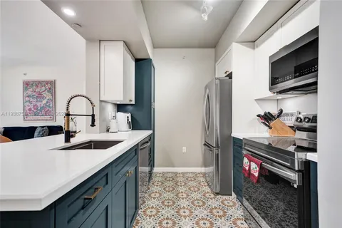a kitchen with stainless steel appliances granite countertop a sink stove refrigerator and cabinets