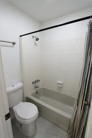 a white toilet sitting next to a bath tub