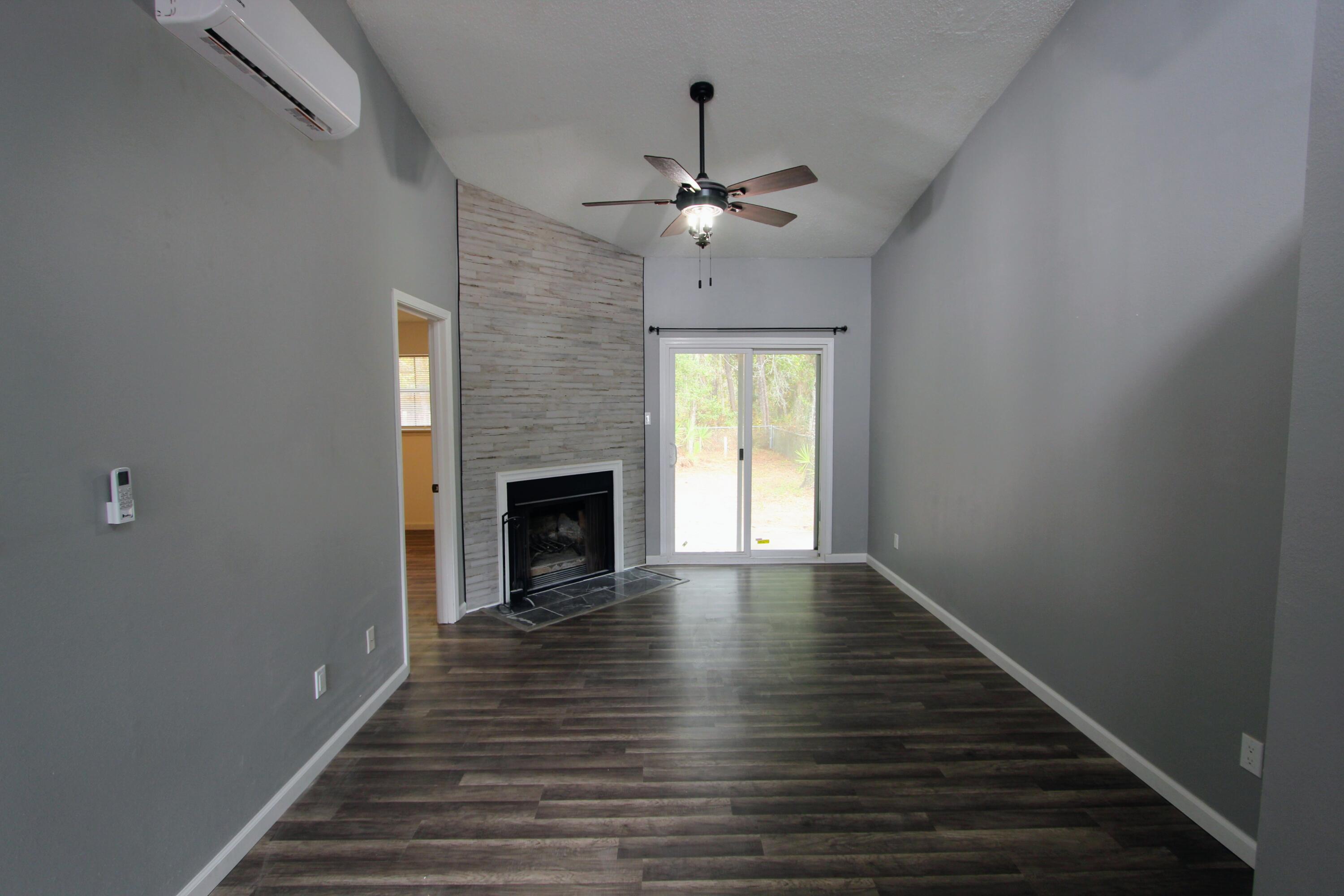 8250 Kause Road Pensacola, FL 32506 - Photo 2 of 28 a view of an empty room with wooden floor fireplace and a window