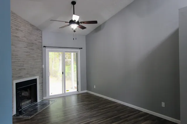 a view of an empty room with wooden floor fireplace and a window