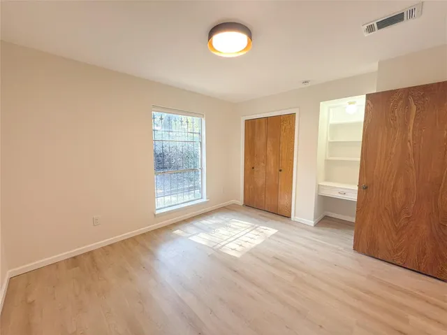 a view of an empty room with wooden floor and window