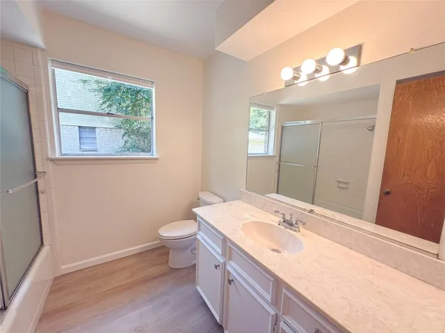 a bathroom with a granite countertop sink a large mirror a toilet and a window