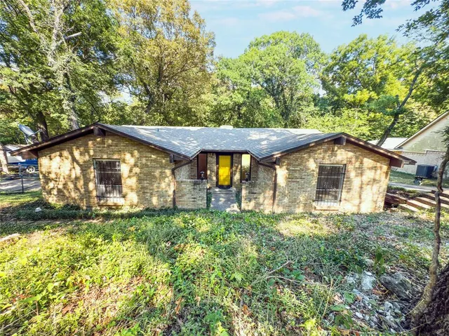 a view of a house with a small yard and large tree