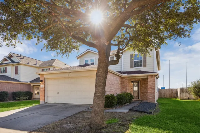 a view of a brick house next to a yard with big trees