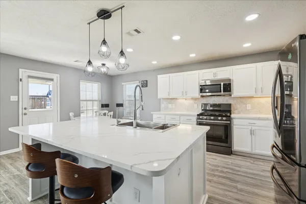 a kitchen with stainless steel appliances granite countertop a sink a stove a refrigerator a center island and cabinets