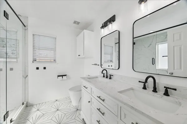 a bathroom with double vanity sink a mirror and a shower