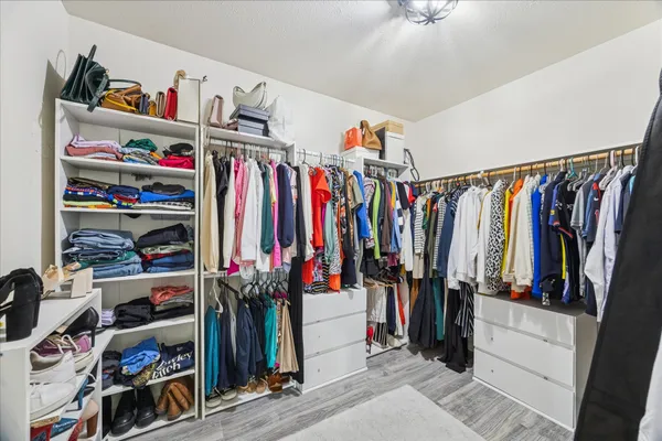 a view of walk in closet with clothes and shoes