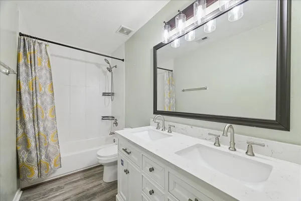 a bathroom with a double vanity sink toilet mirror and shower