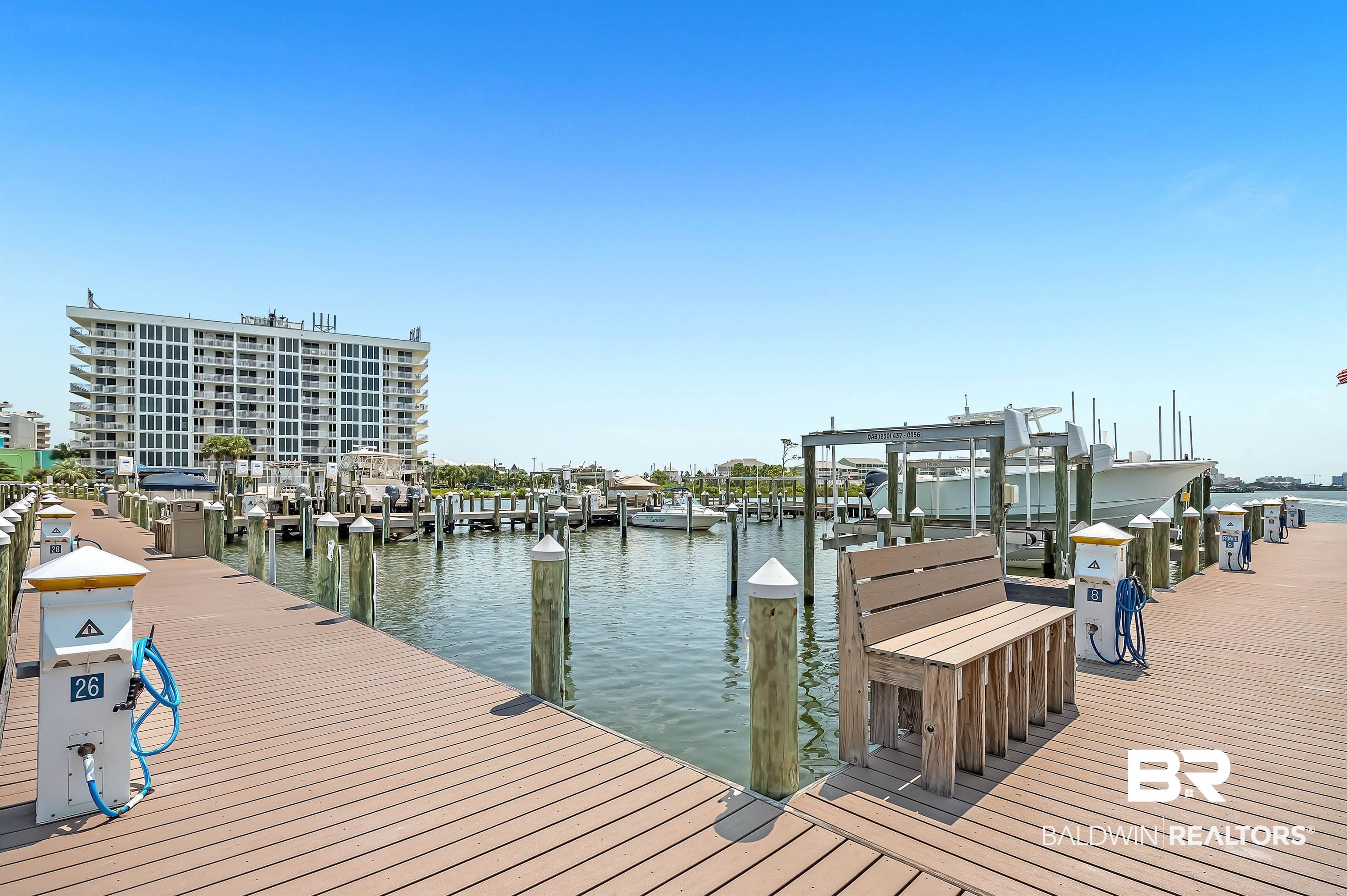 16287 Perdido Key Drive, Unit 105 Pensacola, FL 32507 - Photo 54 of 66 Marina dock featuring composite decking, multiple boat slips, individual power pedestals, and a built-in wooden bench