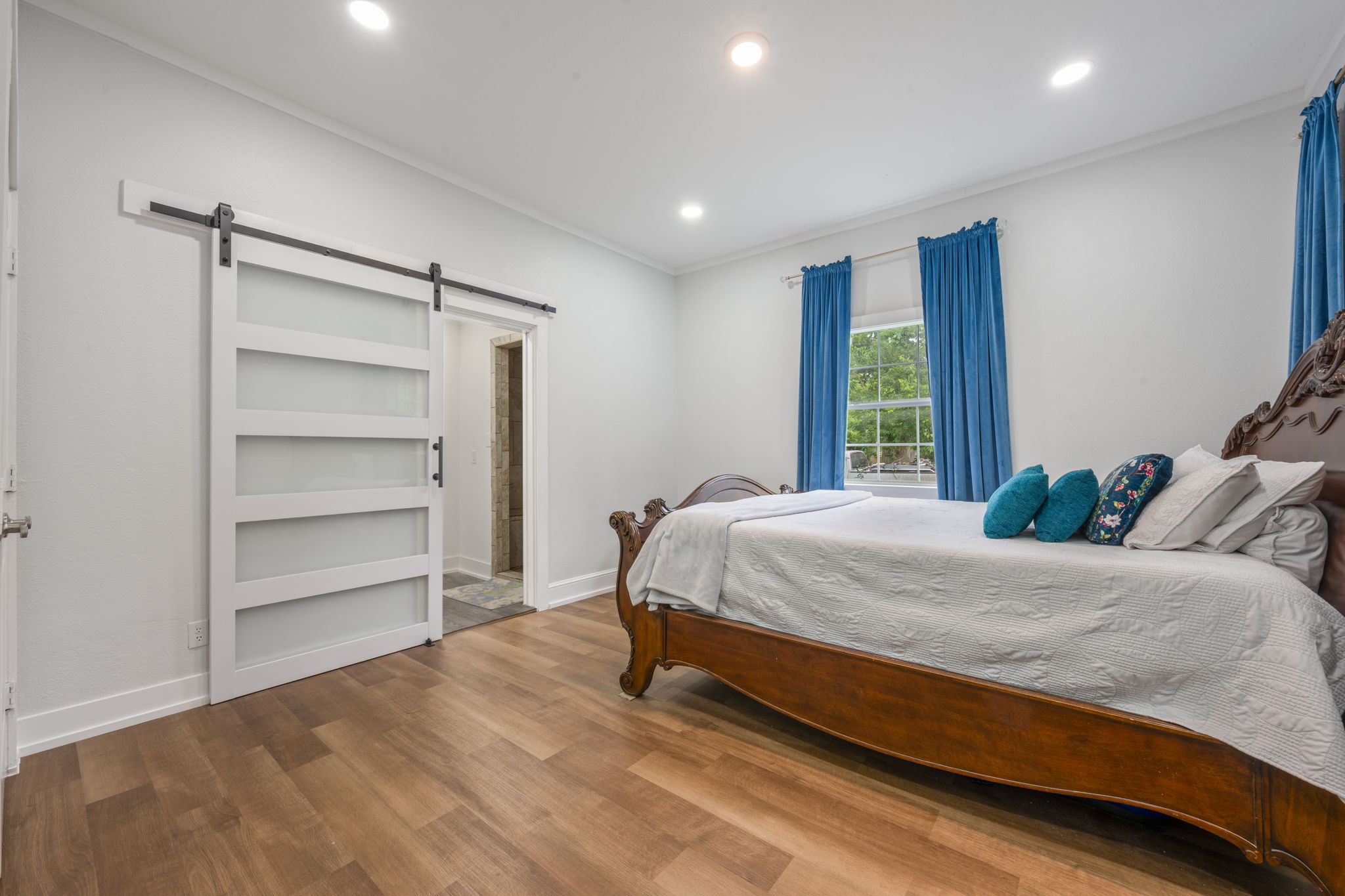 602 East 6th Street Cameron, TX 76520 - Photo 12 of 40 Spacious room featuring wood-finish flooring, recessed lighting, and a white barn door with frosted glass panels