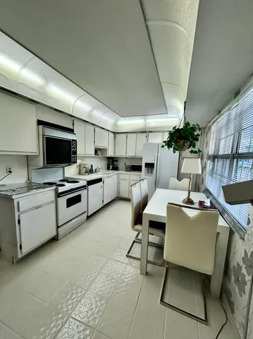 a room with furniture a flat screen tv and kitchen view